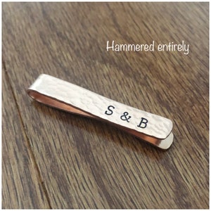 May include: A hammered silver tie bar with the initials "S & B" engraved on it.