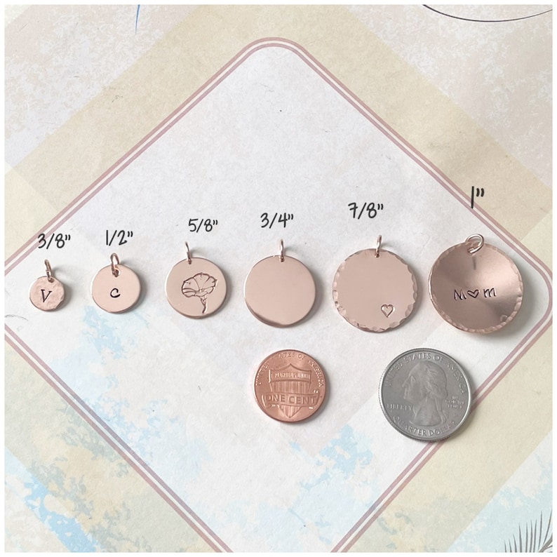 May include: Six rose gold circular charms in sizes 3/8 inch, 1/2 inch, 5/8 inch, 3/4 inch, 7/8 inch, and 1 inch. The charms feature various engravings including the letters V, C, M, a flower, a heart, and a heart between two M letters.