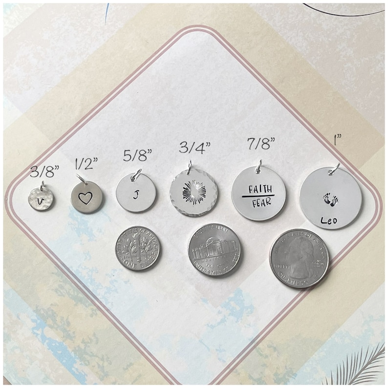 May include: A set of eight silver metal discs with different sizes and designs. The discs are labeled with their diameter in inches: 3/8", 1/2", 5/8", 3/4", 7/8", and 1". The designs include a letter "V", a heart, a letter "J", a starburst, the words "Faith Over Fear", and a pair of footprints with the word "Leo" underneath.