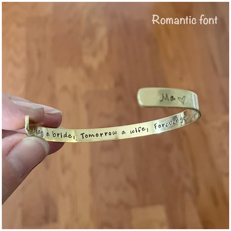 Puede incluir: Pulsera de oro con la inscripci&oacute;n "Today a bride, Tomorrow a wife, Forever your Ma" en una fuente rom&aacute;ntica.