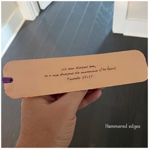 May include: A brown leather bookmark with a quote from Proverbs 27:17, "As iron sharpens iron, so a man sharpens the countenance of his friend." The bookmark has hammered edges.