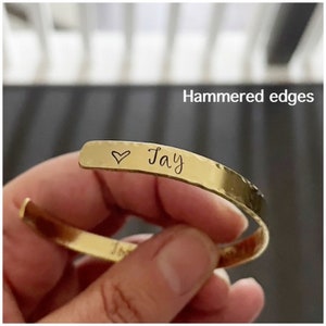 Puede incluir: Pulsera de oro con acabado martillado y un coraz&oacute;n y el nombre "Jay" grabado en ella.