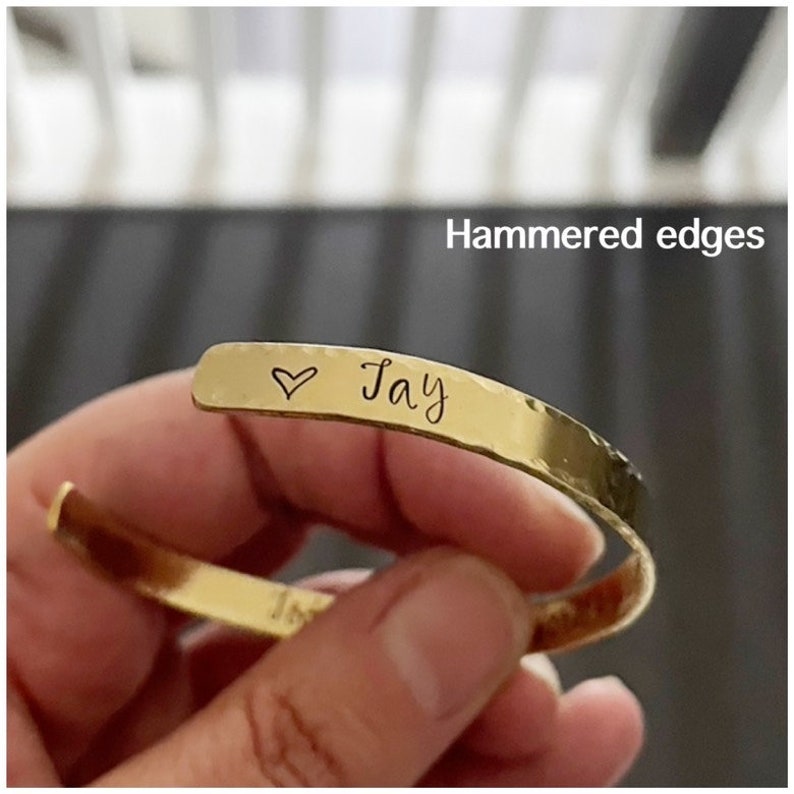 Puede incluir: Pulsera de oro con acabado martillado y un coraz&oacute;n y el nombre "Jay" grabado en ella.