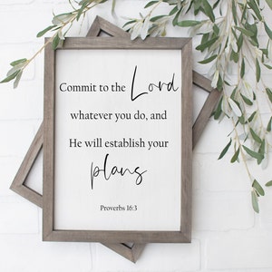 Op de afbeelding: Een ingelijst afdruk met een witte achtergrond en zwarte tekst. De tekst luidt "Commit to the Lord whatever you do, and He will establish your plans. Proverbs 16:3".
