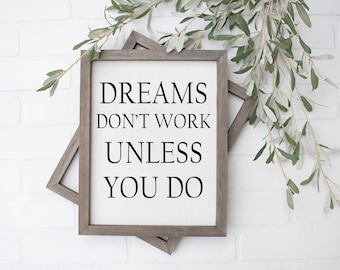 Puede incluir: Dos cuadros enmarcados con el texto "DREAMS DON'T WORK UNLESS YOU DO" en fuente negra. Los marcos son de color gris apagado. Ramas verdes y blancas con hojas en el fondo.