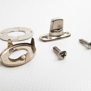 May include: A set of silver-toned metal snap fasteners with two screws. The fasteners are designed for attaching fabric or other materials together.