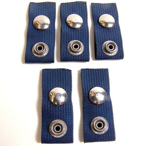 Peut inclure: Six sangles en tissu bleu avec des boutons pression en métal argenté. Chaque sangle a deux boutons pression, un à chaque extrémité.