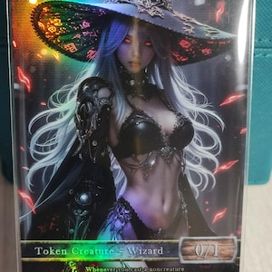 May include: A holographic trading card featuring a female wizard with long white hair, red eyes, and a black outfit. The card reads "WIZARD" at the top and "Token Creature - Wizard" at the bottom, with the number "0/1" on the right.
