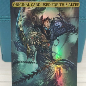 May include: A fantasy art card featuring a dark-skinned figure with a golden helmet and armour, holding a sword and a chain. The figure is surrounded by a swirling, blue and green background. The text "ORIGINAL CARD USED FOR THIS ALTER" is at the top of the card. The text "Art by Eko Handriyanto" is at the bottom of the card.