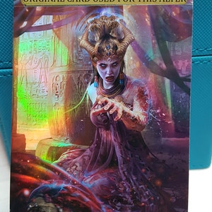 Może przedstawiać: Fantazyjna karta artystyczna przedstawiająca kobietę z koroną i dzikim wyrazem twarzy. Jest ubrana w fioletową szatę i otoczona wirującą, kolorową energią. Karta zawiera tekst "ORIGINAL CARD USED FOR THIS ALTER" u góry.