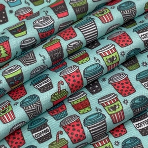 May include: A light blue fabric with a repeating pattern of coffee cups in various designs and colors. The cups feature text like "Coffee," "Latte," and "Hot." Some cups have striped, dotted, or patterned sleeves.