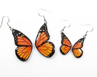 May include: Three pairs of butterfly earrings in different sizes. The earrings are silver with orange and black butterfly wings.