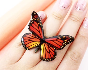 May include: A ring featuring a realistic orange and yellow butterfly with black markings.