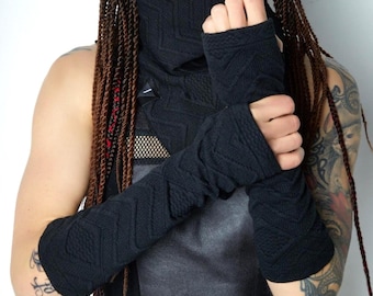May include: A black knit cowl neck scarf and matching fingerless arm warmers featuring a subtle chevron texture. The accessories are crafted from a dark, textured fabric with a consistent geometric pattern throughout the knit design.