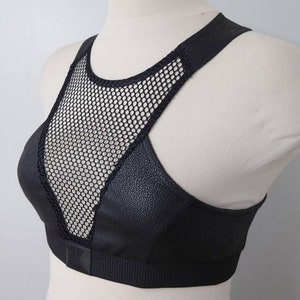 May include: Black sports bra with a mesh panel in the front. The bra has a racerback style and a wide band at the bottom.