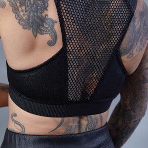 May include: A black sports bra with a mesh back panel. The bra has a racerback style and a wide band at the bottom.