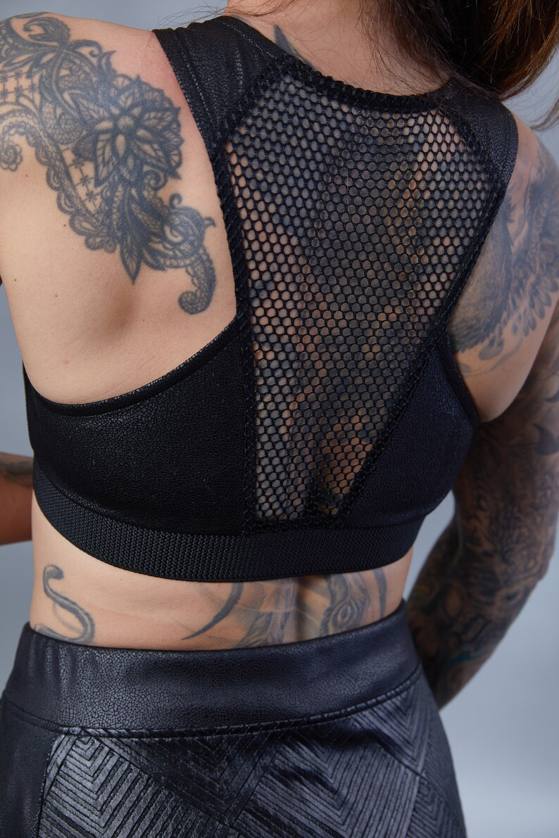 May include: A black sports bra with a mesh back panel. The bra has a racerback style and a wide band at the bottom.