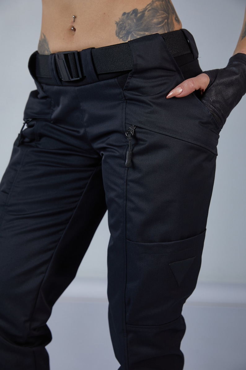 Puede incluir: Pantal&oacute;n cargo negro con m&uacute;ltiples bolsillos y cintur&oacute;n. El pantal&oacute;n tiene un bolsillo con cremallera en la pierna derecha y un parche triangular en la pierna izquierda.