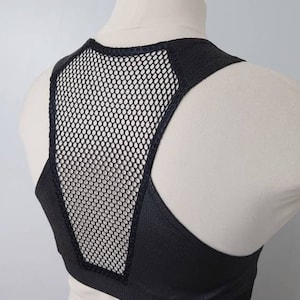 May include: Black sports bra with a mesh panel in the back. The bra has a racerback style and is made of a stretchy, comfortable fabric.