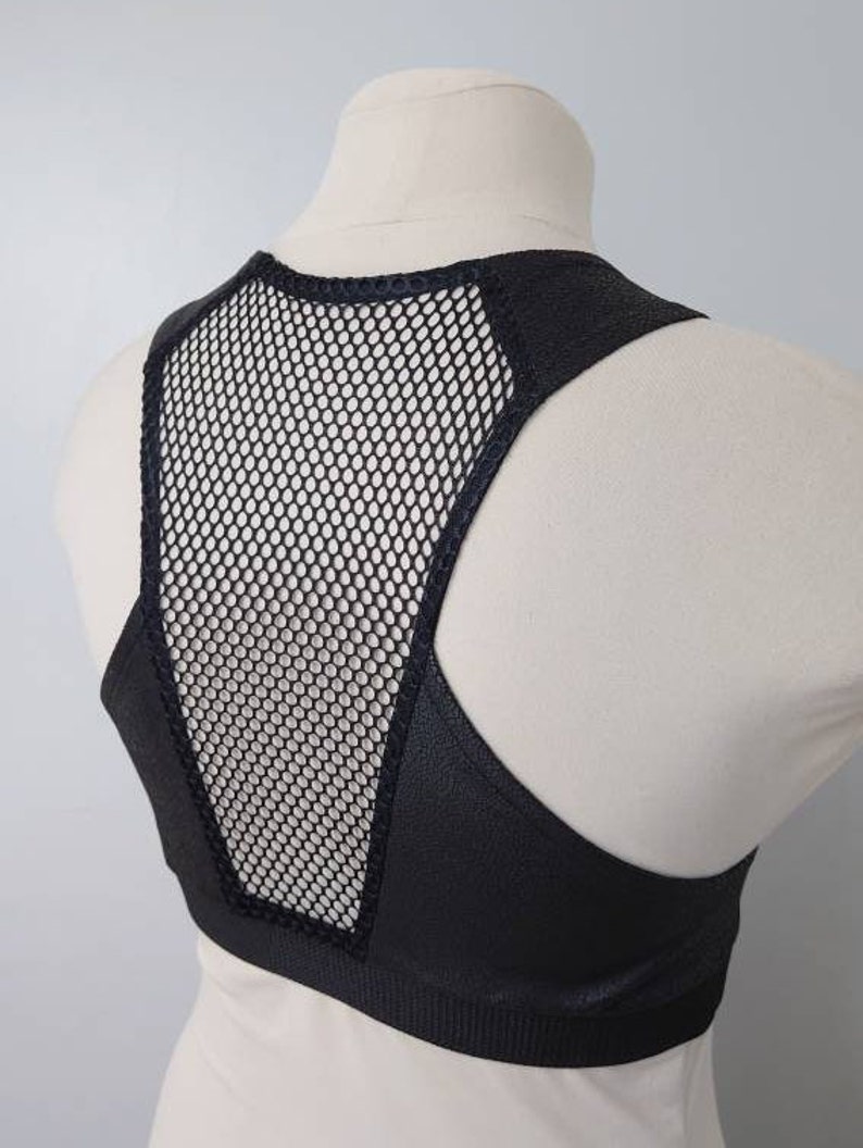 May include: Black sports bra with a mesh panel in the back. The bra has a racerback style and is made of a stretchy, comfortable fabric.