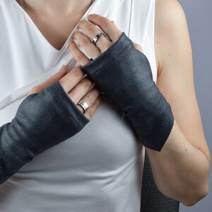 Black faux leather fingerless gloves on crossed arms, steampunk and ren fair style