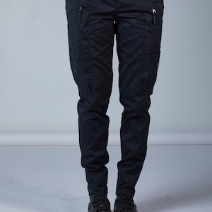 Puede incluir: Pantal&oacute;n cargo negro con cintur&oacute;n negro y bolsillos con cremallera. El pantal&oacute;n est&aacute; hecho de un tejido resistente e impermeable.