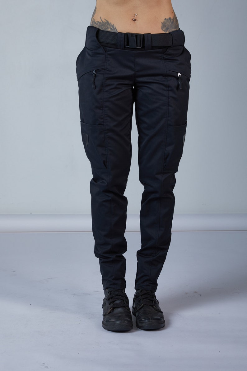 Puede incluir: Pantal&oacute;n cargo negro con cintur&oacute;n negro y bolsillos con cremallera. El pantal&oacute;n est&aacute; hecho de un tejido resistente e impermeable.