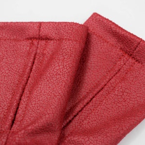 Close-up of red faux leather texture and stitched hem of the arm warmers