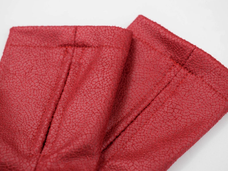Close-up of red faux leather texture and stitched hem of the arm warmers