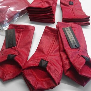 Stack of red faux leather arm warmers with ZOLNAR labels