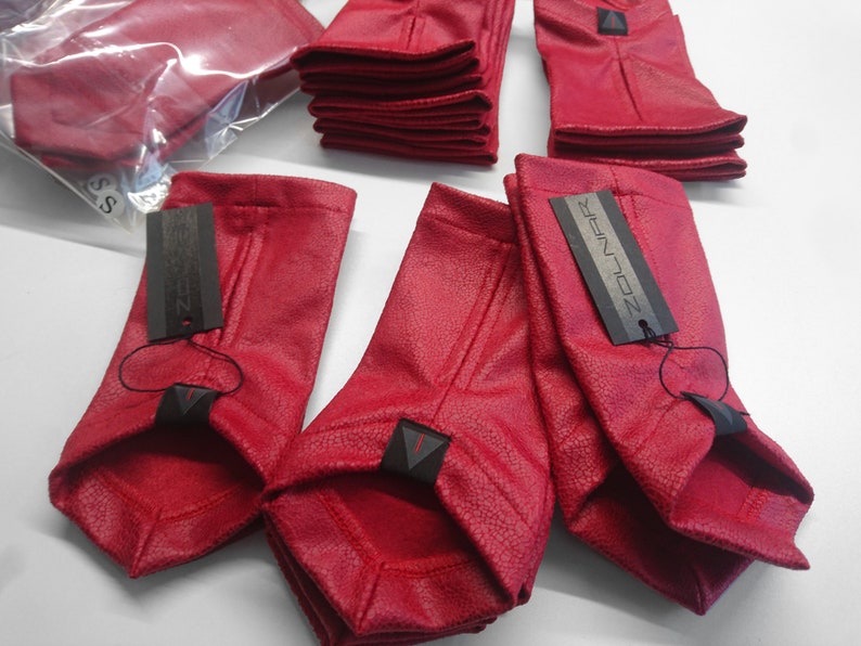 Stack of red faux leather arm warmers with ZOLNAR labels
