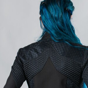 May include: A black jacket with a star-shaped design on the back. The jacket has a quilted texture and a zipper closure.