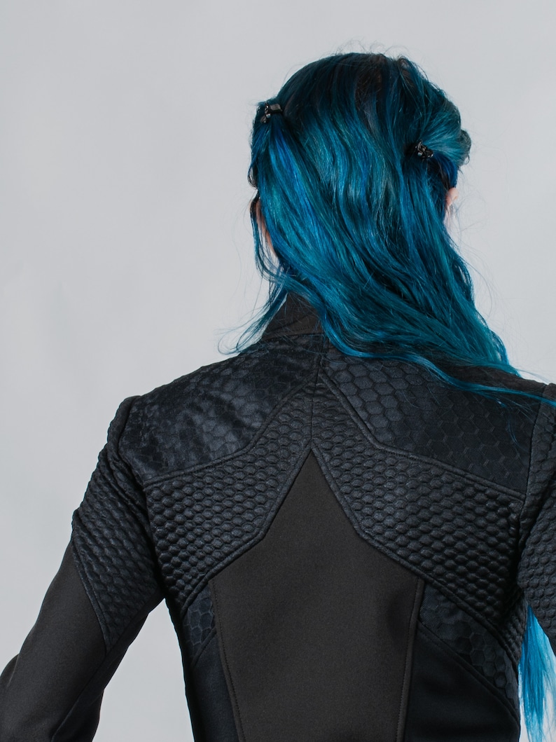 May include: A black jacket with a star-shaped design on the back. The jacket has a quilted texture and a zipper closure.