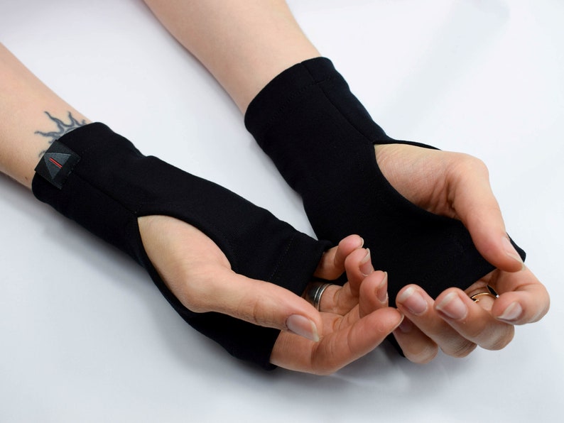 May include: A pair of black fingerless gloves with a thumb hole. The gloves are made of a soft, stretchy fabric and have a simple design.