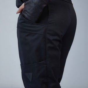 Puede incluir: Pantal&oacute;n negro con un gran bolsillo cargo en la pierna izquierda. El bolsillo tiene un parche triangular con un logotipo.