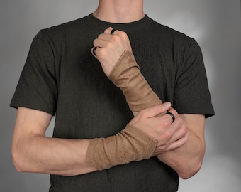 May include: A pair of tan wrist warmers featuring a fine, textured, speckled pattern. These arm sleeves are crafted from a soft, flexible material that gathers slightly around the forearms, providing a snug fit without any visible closures.