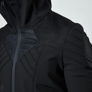 May include: A black hooded jacket featuring a high collar, a full-length front zipper, and textured mesh panels on the chest and shoulders. The garment includes padded, stitched detailing across the upper torso and sleeves for a structured look.