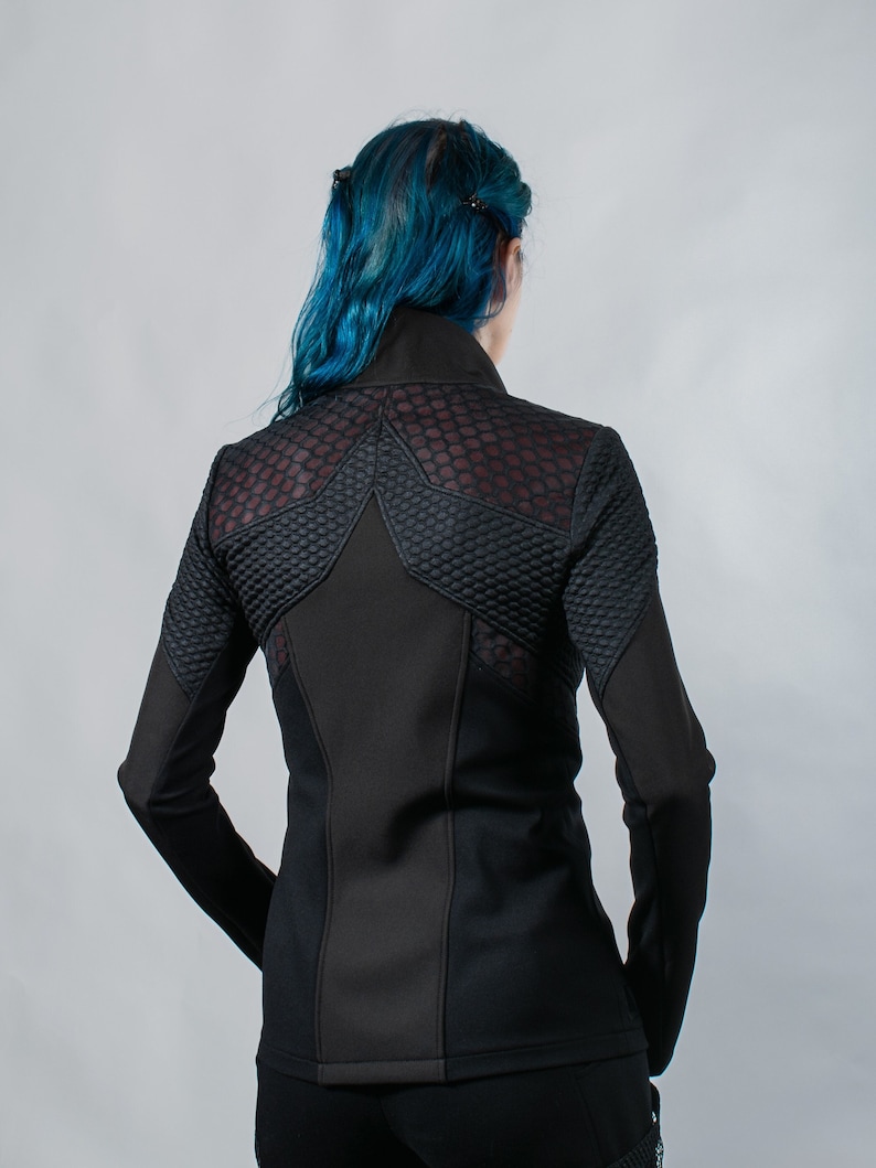 May include: Black long-sleeved jacket with a geometric design on the back. The jacket has a mesh panel on the back and a high collar.