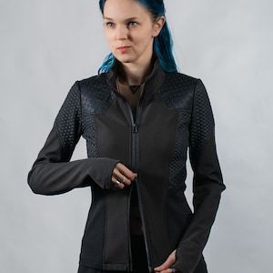 May include: A black zippered jacket with a textured design on the shoulders and sleeves. The jacket has a high collar and a slim fit.