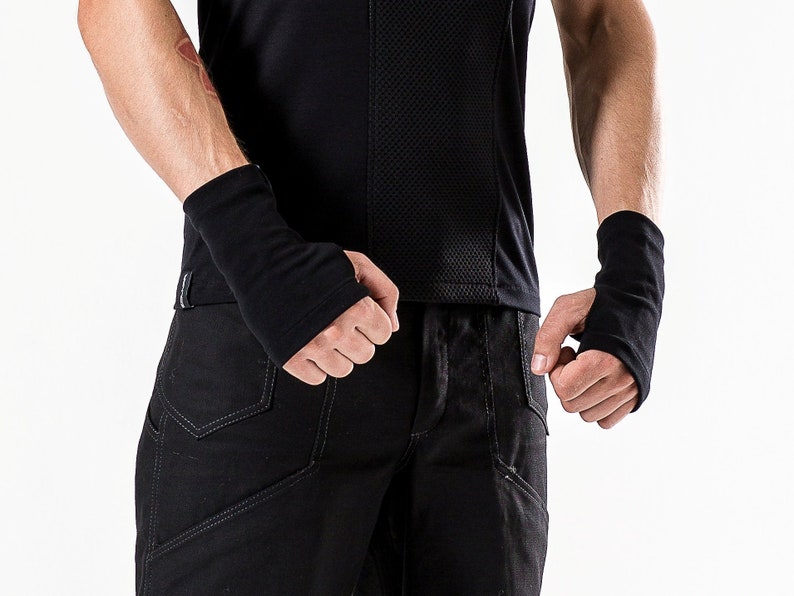 May include: A pair of black wrist warmers made of a soft, stretchy fabric. The warmers are worn on both wrists.