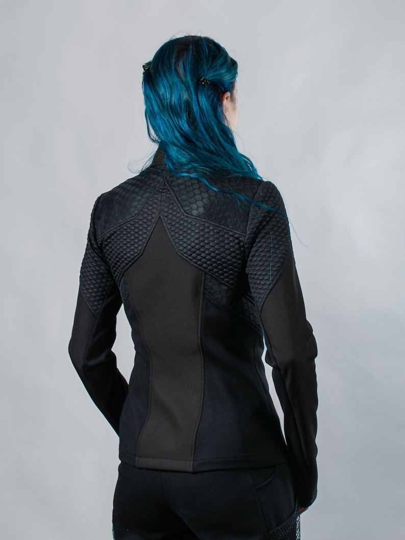May include: Black quilted jacket with a star-shaped design on the back. The jacket has a zipper closure and long sleeves.