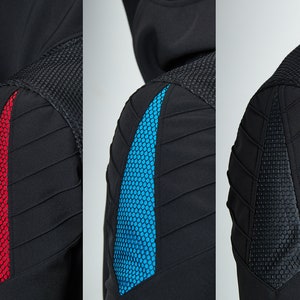 May include: A black hooded jacket featuring a textured mesh shoulder panel and a triangular insert on the upper arm. The insert is available in three color variations: a vibrant red, a bright blue, and a solid black, all with a honeycomb pattern.