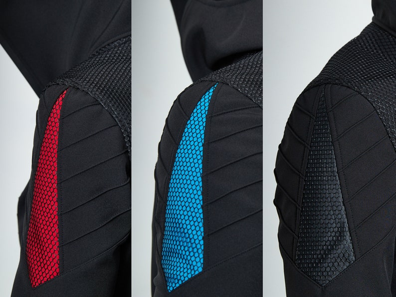 May include: A black hooded jacket featuring a textured mesh shoulder panel and a triangular insert on the upper arm. The insert is available in three color variations: a vibrant red, a bright blue, and a solid black, all with a honeycomb pattern.