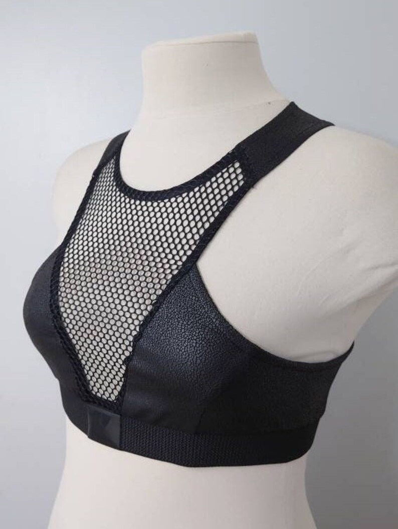 May include: Black sports bra with a mesh panel in the front. The bra has a racerback style and a wide band at the bottom.