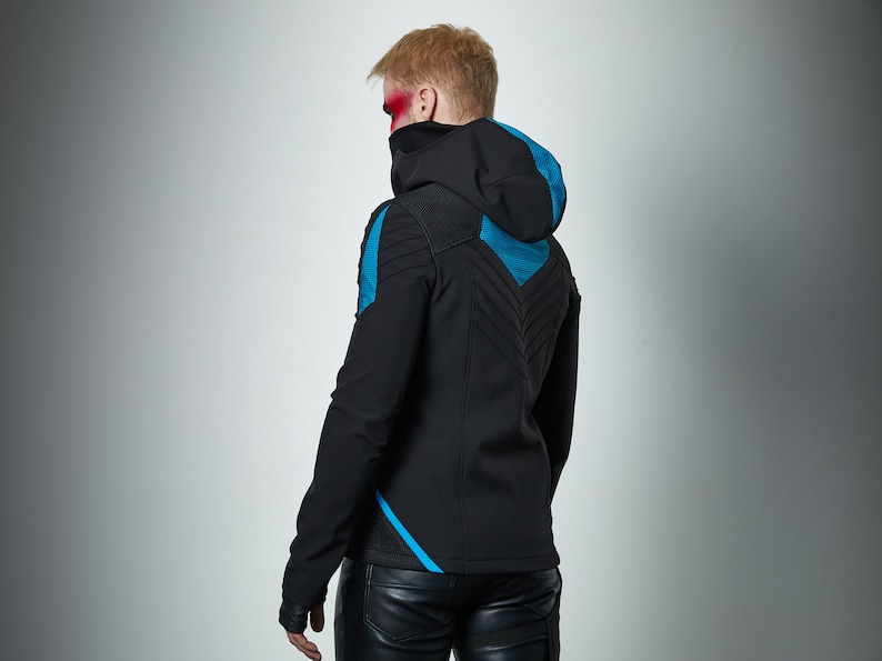 May include: A black hooded jacket featuring bright blue accents on the shoulders and back. The jacket has a high collar, long sleeves, and a textured chevron pattern on the back panel. It is paired with black trousers that have a smooth, dark finish.