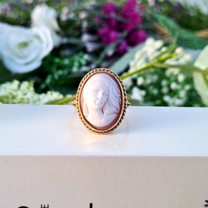 Op de afbeelding: Een gouden ring met een cameo met een gegraveerd portret van een vrouw met lang haar. De cameo is gezet in een ovale gouden lijst.
