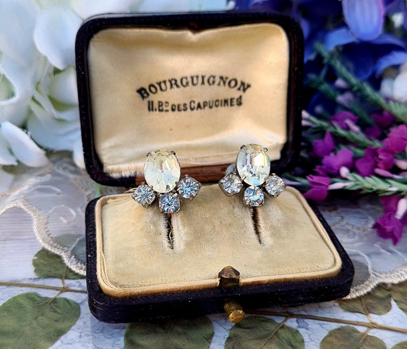 May include: A pair of vintage clear crystal earrings with a cluster of smaller crystals, in a black velvet jewelry box with the inscription "Bourguignon 11, Rue des Capucines".