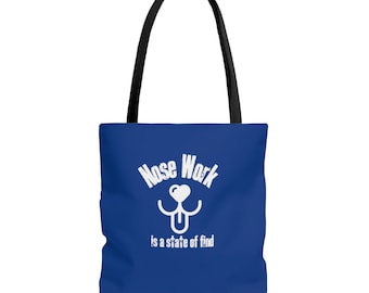 May include: A blue tote bag with white text that reads "Nose Work is a state of find". A white silhouette of a dog's nose with a heart and tongue is above the text.