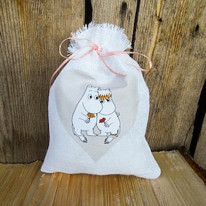 May include: White fabric gift bag with a pink ribbon and a printed image of two cartoon characters holding hands. The characters are white with black outlines and are holding a red flower.