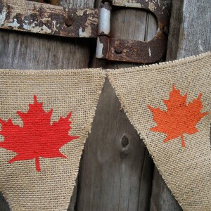 May include: A burlap banner with red and orange maple leaf designs. The banner is strung together with twine and is perfect for a Canadian themed party or celebration.